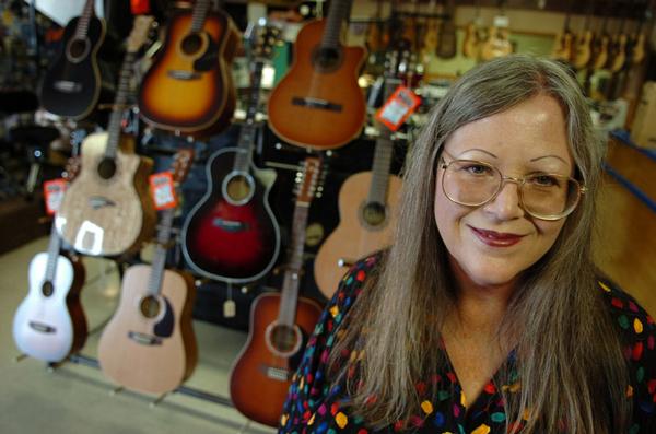 Joan McCarty, owner of McCarty Music on Kemp, poses for a portrait in front of a stand of guitars